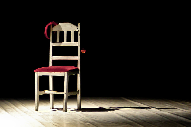 one chair in the spotlight on an empty stage