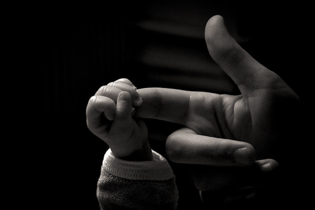 baby's hand hanging on to an adult finger, a primal human connection
