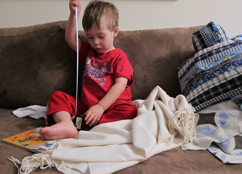 boy on a messy couch playing with a tape measure