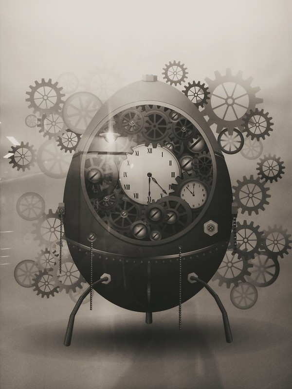 egg-shaped contraption holding a clock and surrounded by clockwork wheels and gears
