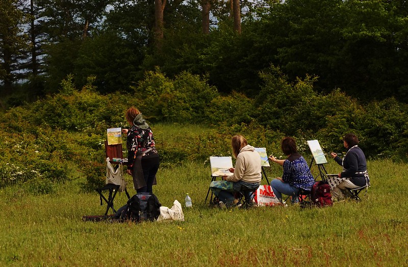 a line of plein aire painters in a field